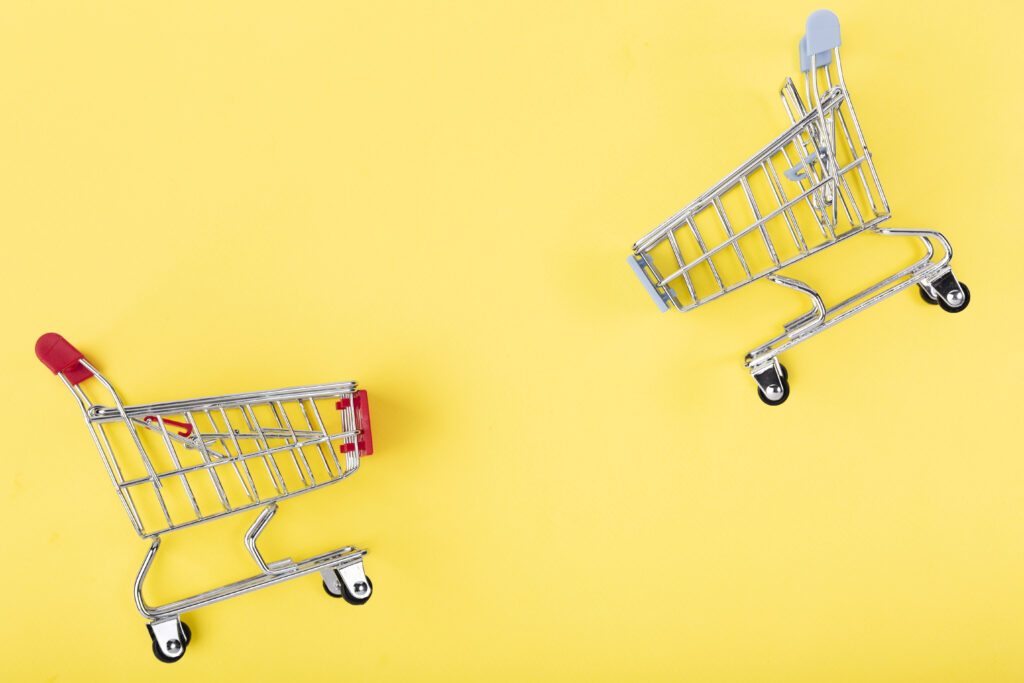 Two shopping baskets - shopping carts - on a yellow background.